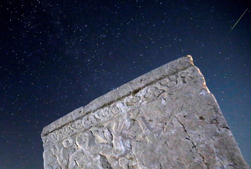Um meteoro passa pelas estrelas no céu noturno acima de lápides medievais durante a chuva de meteoros Perseidas em Radimlja, perto de Stolac, na Bósnia e Herzegovina — Foto:  Dado Ruvic/Reuters