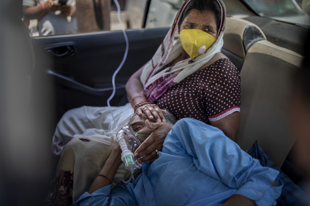 Homem recebe oxigênio dentro de carro em Nova Delhi, na Índia, neste sábado (24). Com falta do insumo, templos estão oferecendo "sessões de oxigênio" de graça para pacientes com Covid-19 à espera de um leito de hospital. — Foto: AP Photo/Altaf Qadri
