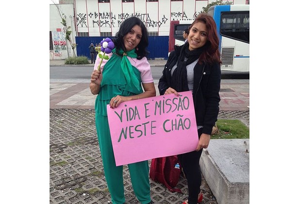 Antes do início dos protestos, manifestantes exibem cartaz e rosas (Foto: Graziela Salomão)