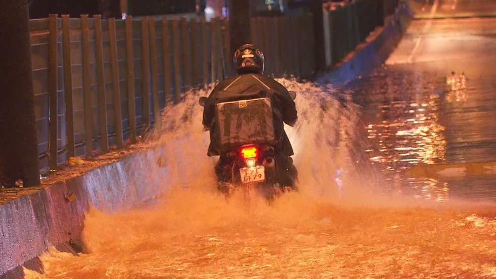Motociclista atravessa via alagada durante chuva em SP — Foto: Reprodução/TV Globo
