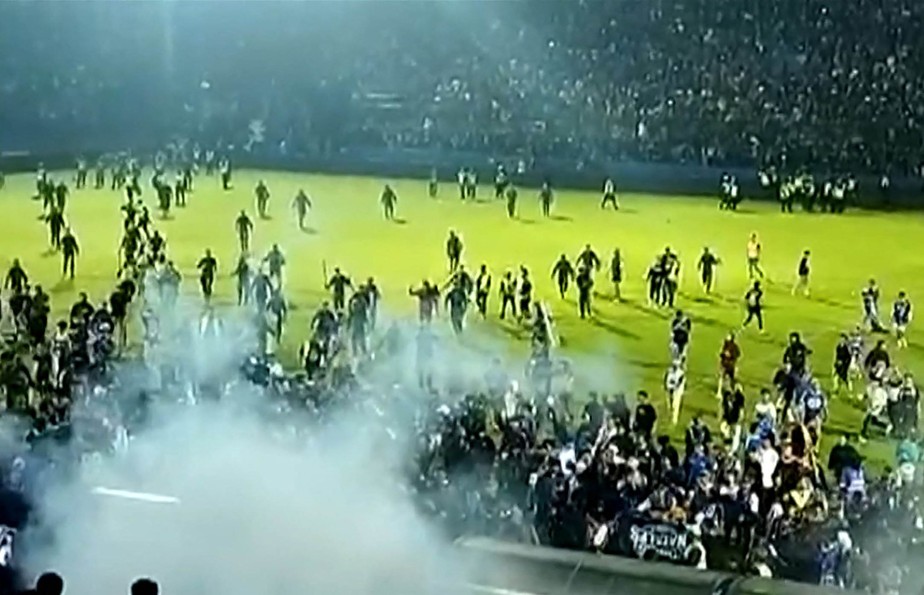 Captura de tela de um vídeo da AFPTV feito em 1º de outubro de 2022 mostra gás lacrimogêneo na multidão enquanto há correria em campo após uma partida de futebol entre Arema FC e Persebaya Surabaya no estádio Kanjuruhan em Malang, Java Oriental, na Indonésia