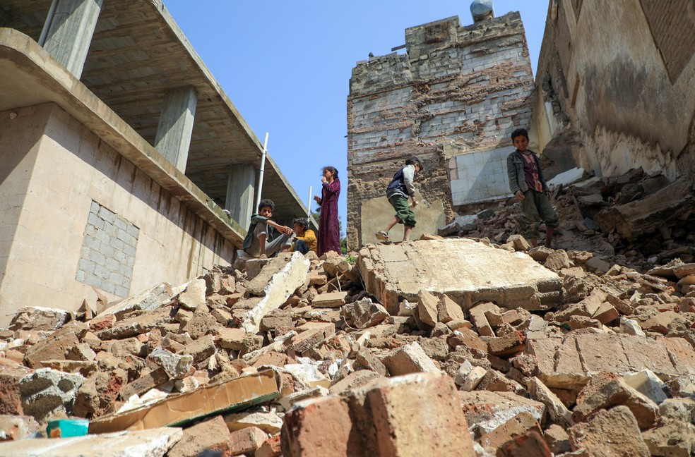 Crianças sobre pilha de destroços no Iêmen — Foto: MOHAMMED HUWAIS / AFP