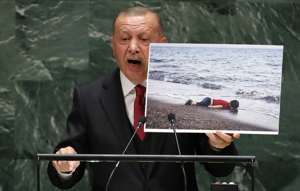 O presidente da Turquia, Recep Tayyip Erdogan, segura a foto do menino sírio Aylan Kurdi, de origem curda, que morreu afogado no Mar Mediterrâneo 2015, enquanto a família tentava fazer a travessia da Síria à Europa. — Foto: Lucas Jackson/Reuters