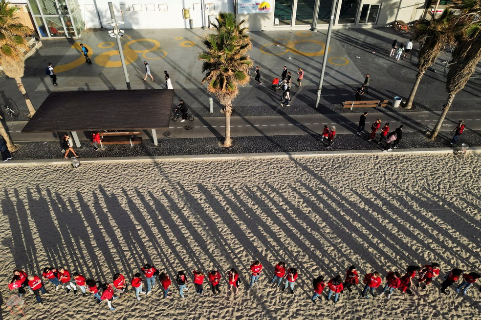 Mulheres vestidas de vermelho participam de uma manifestação contra a reforma judicial do governo israelense e para marcar o Dia Internacional da Mulher, em uma praia em Tel Aviv, Israel, em 8 de março de 2023  — Foto: REUTERS /Amir Cohen