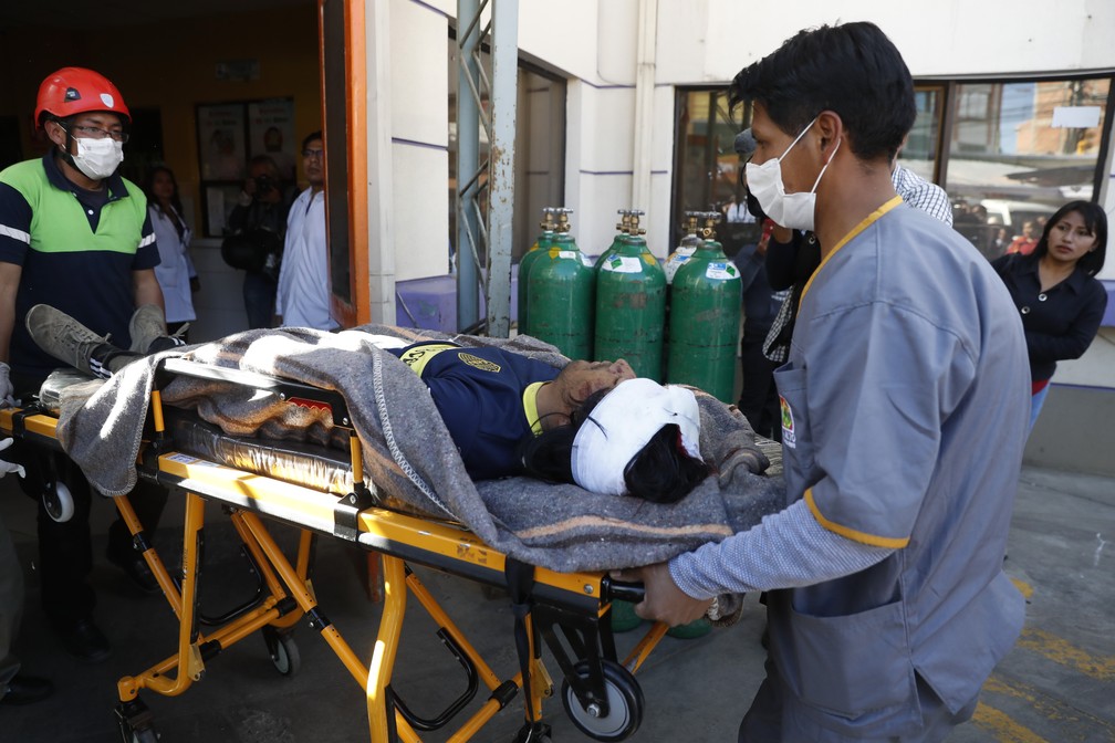 Paramédicos transportam ferido em confronto entre forças de segurança e manifestantes em El Alto, na Bolívia, nesta terça-feira (19) — Foto: Natacha Pisarenko/AP Photo