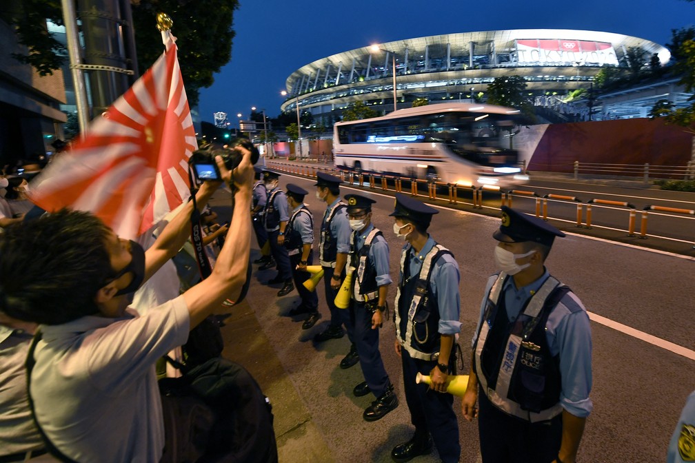 Policiais ficam em linha na frente de torcedores reunidos em frente ao Estádio Olímpico durante a cerimônia de abertura dos Jogos Olímpicos de Tóquio, no Japão — Foto: Kazuhiro Nogi/AFP