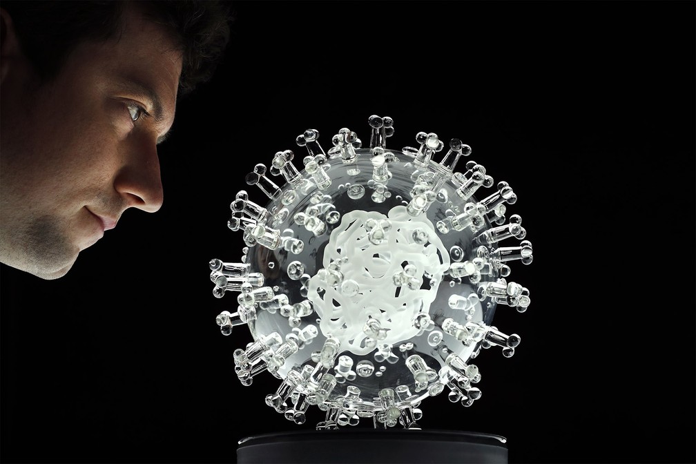 Escultura de vidro representando o coronavírus é apresentada no estúdio do artista britânico Luke Jerram, em Bristol, na Inglaterra. Intitulada 'coronavirus - COVID-19', a peça de 23 cm de diâmetro representa o vírus em seu tamanho aumentado 1 milhão de vezes e faz tributo ao esforço médico e científico para combater a pandemia — Foto: Adrian Dennis/AFP