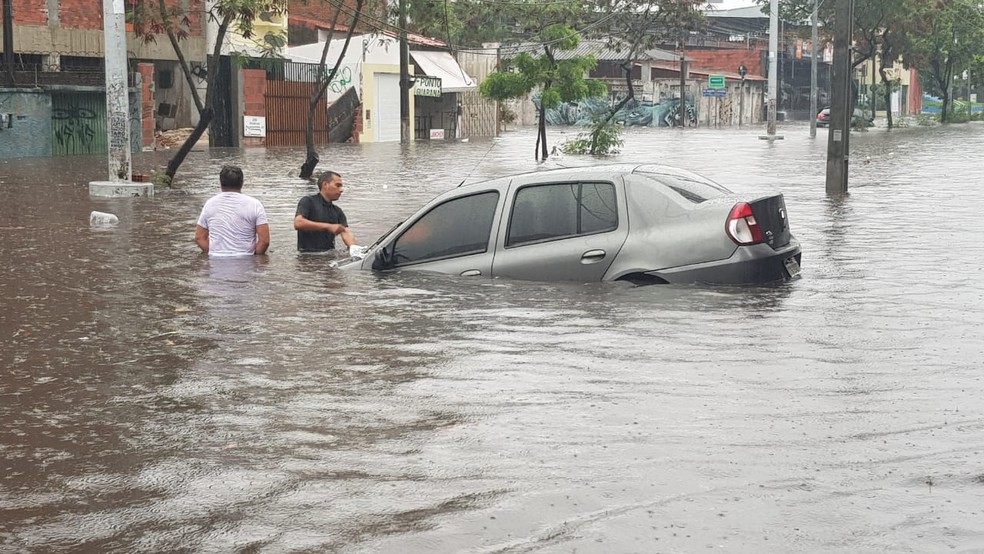 Homens tentam tirar carro parcialmente submerso na Av. Heráclito Graça, em Fortaleza — Foto: José Leomar/SVM