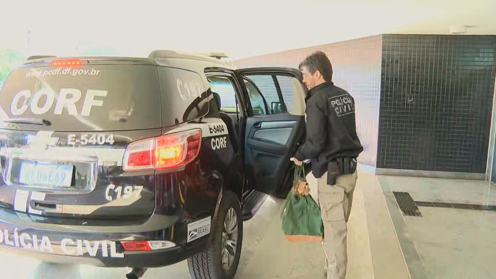 Policial carrega materiais apreendidos na operação Looping 2, da Polícia Civil do DF — Foto: TV Globo/Reprodução