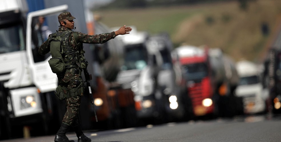 Militar orienta trânsito ao lado de fila de caminhões parados em rodovia durante a paralisação de maio (Foto: Reuters)