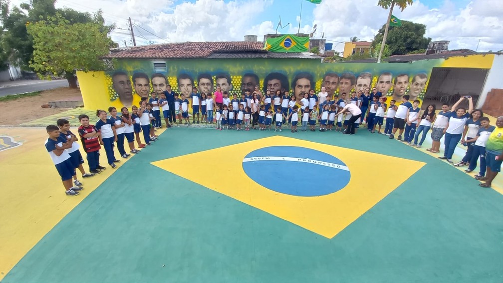 Estudantes visitam rua pintada com jogadores do Brasil. Uma das paredes homenageia craques que conquistaram títulos pela seleção. — Foto: Reprodução 