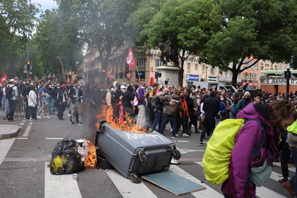 Manifestantes marcham ao lado de uma lata de lixo em chamas durante protesto em Toulouse, sudoeste da França, em 1º de maio de 2023 — Foto: Charly Triballeau/AFP