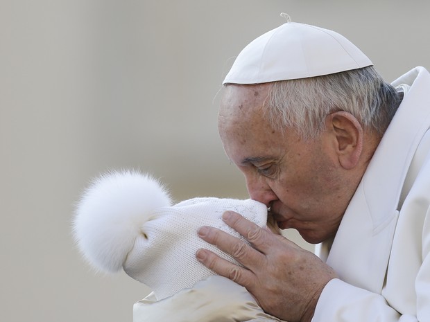 Papa Francisco beija uma criança ao chegar para sua audiência geral nesta quarta-feira (16) no Vaticano (Foto: Gregorio Borgia/AP)