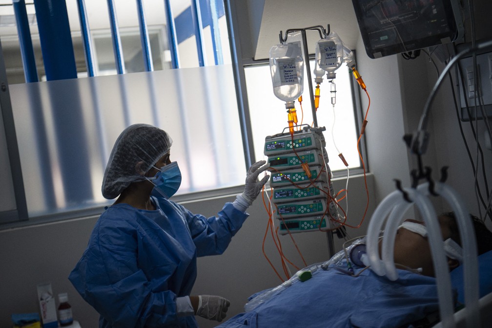 Profissional de saúde cuida de paciente com Covid-19 em UTI em um hospital de Lima, no Peru, na quinta-feira (12). — Foto: Ernesto Benavides / AFP
