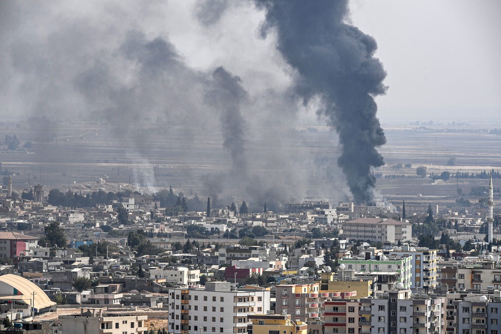 Foto tirada da cidade turca de Ceylanpinar mostra bombardeio na cidade síria de Ras al-Ain nesta quarta-feira (16)  — Foto: Ozan Kose / AFP