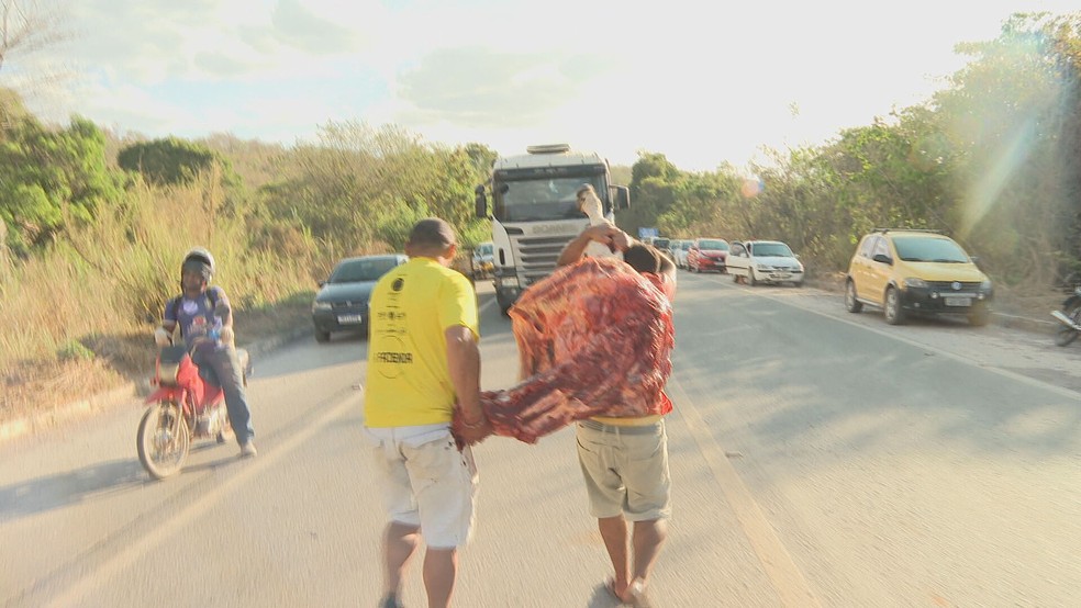 População leva embora pedaços de carne de bois mortos em rodovia, no DF — Foto: Lázaro Aluízio/TV Globo