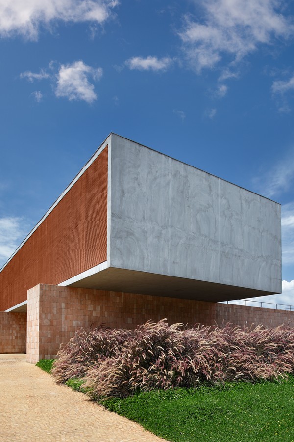 o grande monolito de concreto, com painel de muxarabi, se apoia sobre pilares de tijolos