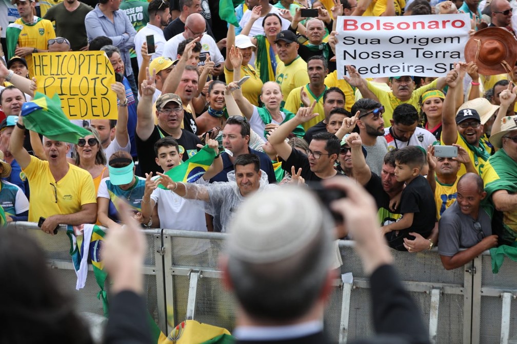 Um grupo de jornalistas israelenses é saudado efusivamente pelo público próximo à grade, com gritos de 'Israel' e 'Jerusalém', ao chegar à área de imprensa na Praça dos Três Poderes — Foto: Fábio Tito/G1