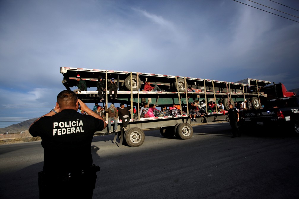 Um policial tira fotos de migrantes na carroceria de um caminhão em Saltillo, no México, onde ficarão em um abrigo temporário enquanto seguem em jornada para os EUA — Foto: Daniel Becerril/Reuters