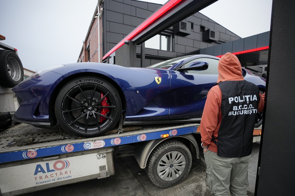 Policial romeno olha para Ferrari do lutador e influencer Andrew Tate, acusado de envolvimento em casos de estupro e tráfico humano,  apreendida em 14 de janeiro de 2023 — Foto: Andreea Alexandru/AP