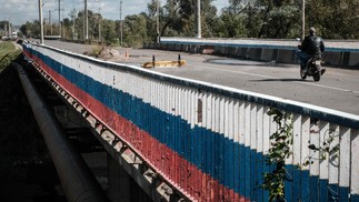 Cerca lateral da ponte sobre o rio Oskil é pintada na cor da bandeira russa em Kupiansk, região de Kharkiv, em meio à invasão russa da Ucrânia — Foto: Yasuyoshi CHIBA / AFP