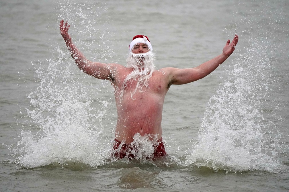 Patrick Corkery usa um chapéu de Papai Noel e barba durante um mergulho no dia de Natal na Irlanda, neste sábado (25) — Foto: Niall Carson/PA via AP