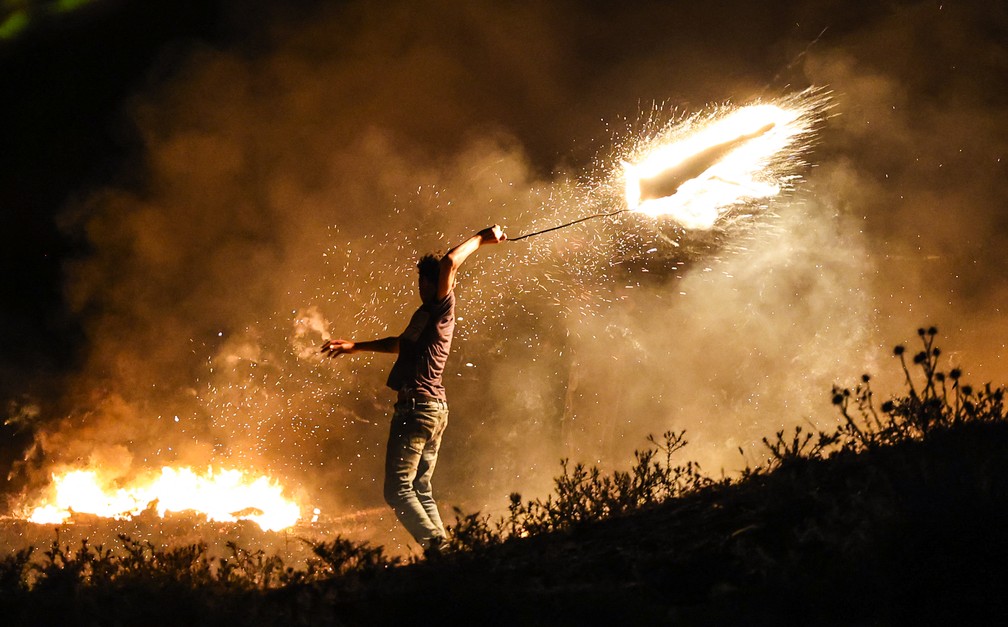 Homem na Faixa de Gaza atira nesta terça-feira (15) objeto incendiado na direção do território israelense — Foto: Mahmud Hams/AFP