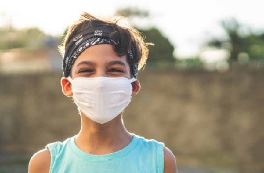 Menino de bandana sorrindo com máscara antes de praticar esporte (Foto: Getty Images)