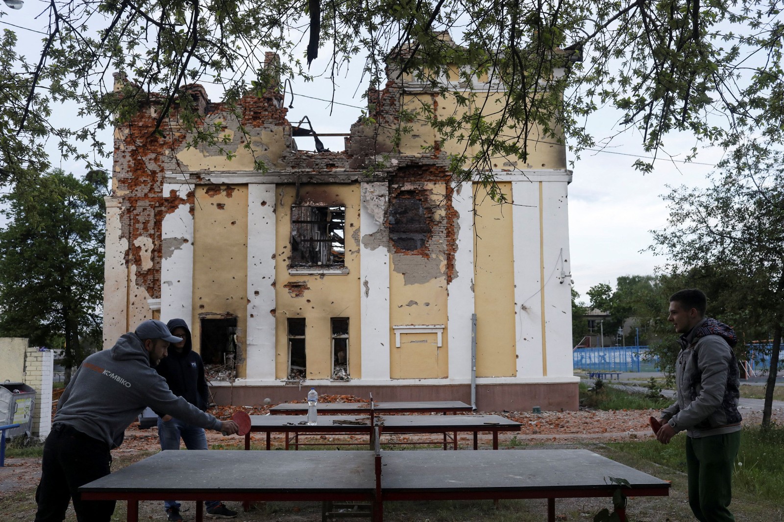 Ex-alunos jogam pingue-pongue no playground de uma escola destruída, em Kharkiv — Foto: Ricardo Moraes/REUTERS
