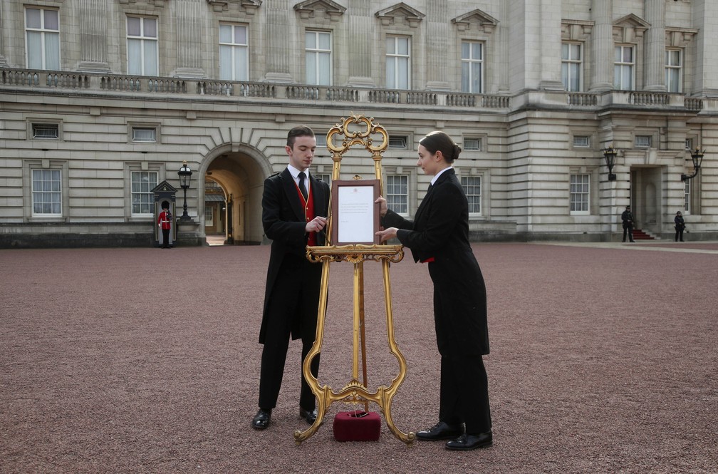 Funcionários do Palácio de Buckingham colocam o anúncio oficial do nascimento em exposição, na segunda-feira (6). — Foto: Yui Mok/Pool Photo via AP