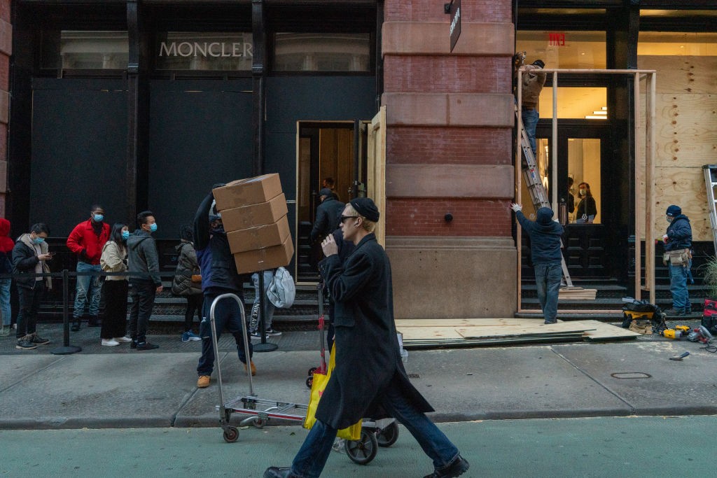 NEW YORK, NY - NOVEMBER 2: People stand in line outside a Moncler store as workers board up the windows to the store on November 2, 2020 in New York City. Property owners are preparing and boarding up store fronts as local and state officials warn of viol (Foto: Getty Images)