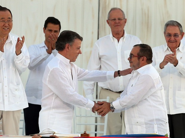 Juan Manuel Santos, presidente da Colômbia, e Rodrigo Londoño, chefe das Farc, se cumprimentam nesta segunda-feira (26) após assinar o acordo de Paz em Cartagena (Foto: Fernando Vergara/AP)