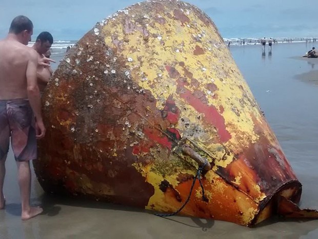 Banhistas observam grande objeto que encalhou em Praia Grande, SP (Foto: Luciane Knapick/VC no G1)