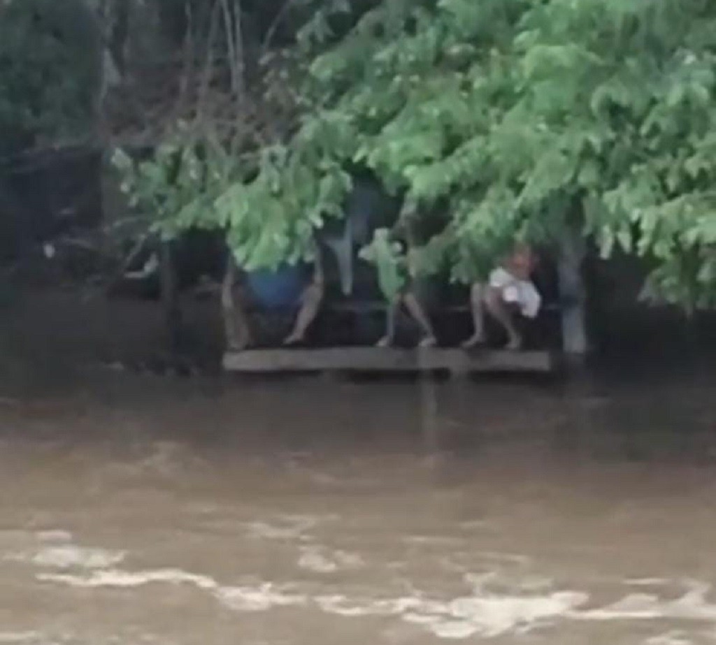 Família usa mesa de madeira para se proteger de cabeça d'água em cachoeira de Piraí; veja vídeo