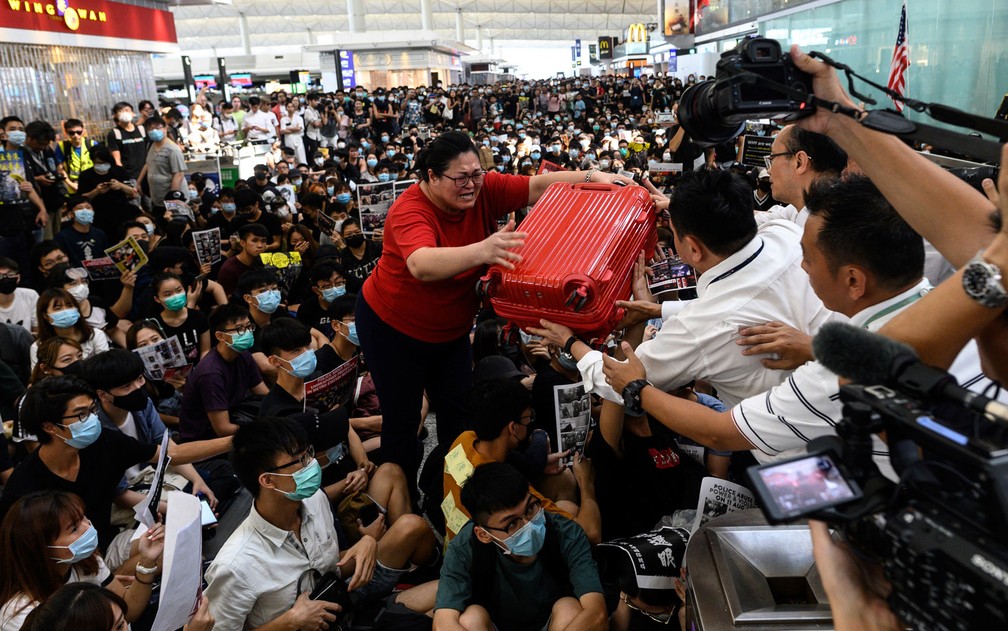 Alguns se esforçaram para passar por multidões antes que os voos fossem suspensos — Foto: Philip Fong/AFP