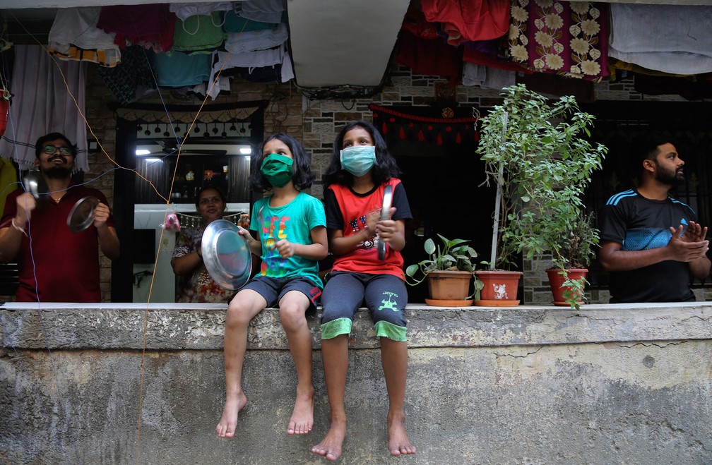 Pessoas batem palmas e panelas durante demonstração de agradecimento aos profissionais de saúde em Mumbai, na Índia, em 22 de março  — Foto: Rafiq Maqbool/AP