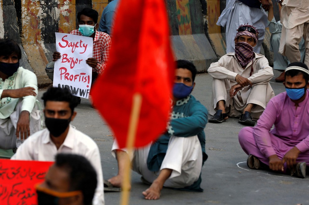 Ativistas de várias organizações trabalhistas, usando máscaras protetoras como medida preventiva contra a propagação de coronavírus (COVID-19), participam de um comício exigindo melhorias nas condições de trabalho, durante o Dia Internacional do Trabalho, em Karachi, no Paquistão — Foto: Akhtar Soomro/Reuters
