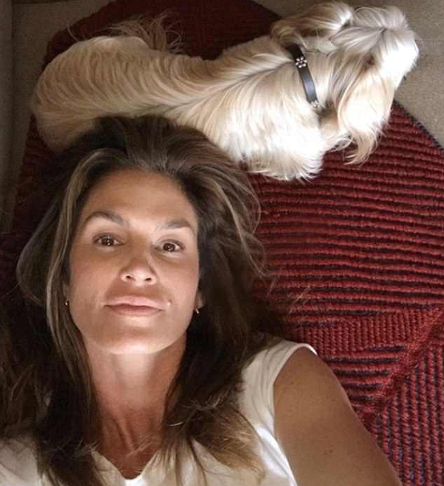 A modelo Cindy Crawford sem maquiagem e deitada em cima de seu cachorrinho (Foto: Instagram)