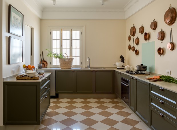 Panelas e tachos de cobre foram dispostos na parede para enfeitar a cozinha verde-oliva (Foto: André Nazareth/Divulgação)