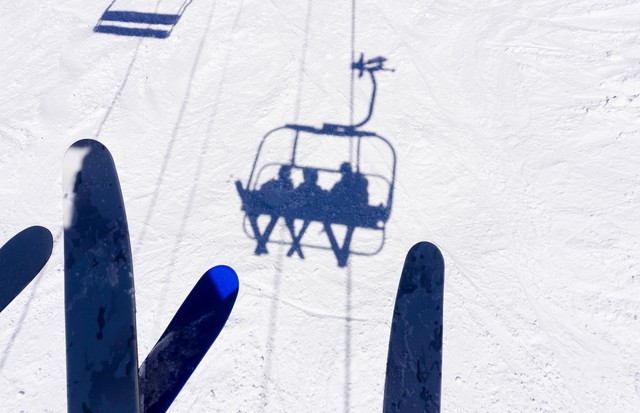 Skiers on Chairlift Shadows on Snow - Looking down from chairlift with three skiers casting crisp shadows below. (Foto: Getty Images/iStockphoto)