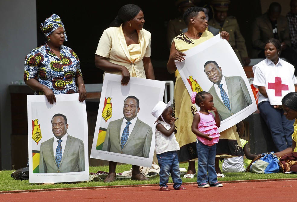 Mulheres seguram retrato de Emmerson Mnangagwa antes de início de cerimônia de posse em Harare, no Zimbábue (Foto: Tsvangirayi Mukwazh/AP Photo)