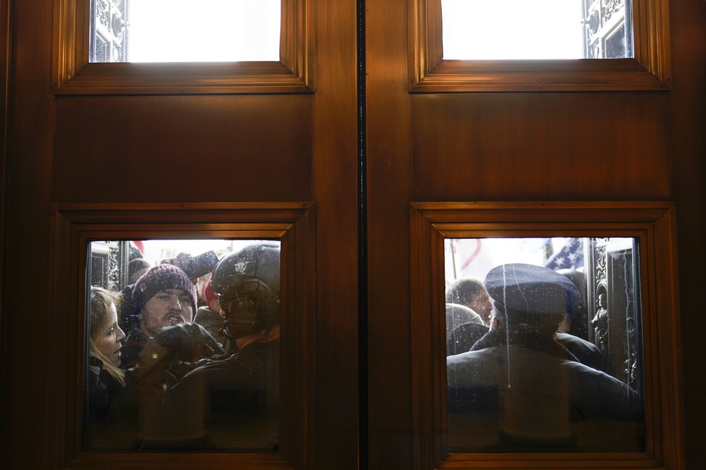 Policiais do Capitólio, em Washington, tentam segurar extremistas pró-Trump em uma das portas que dão acesso ao prédio, nesta quarta-feira (6) — Foto: Andrew Harnik/AP