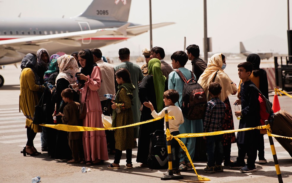 Civis afegãos se preparam para embarcar em avião para deixar o país no Aeroporto Internacional Hamid Karzai, em Cabul, na quarta-feira (18) — Foto: Staff Sgt. Victor Mancilla/U.S. Marine Corps via AP