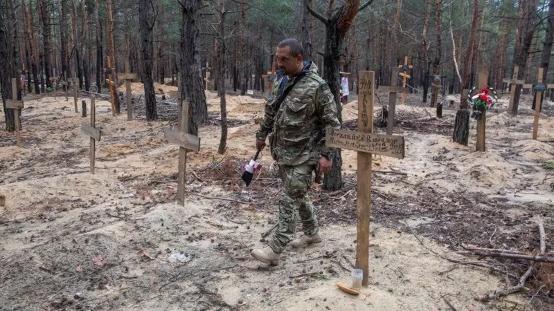 Um soldado caminha entre os túmulos encontrados na floresta (Foto: REUTERS via BBC)