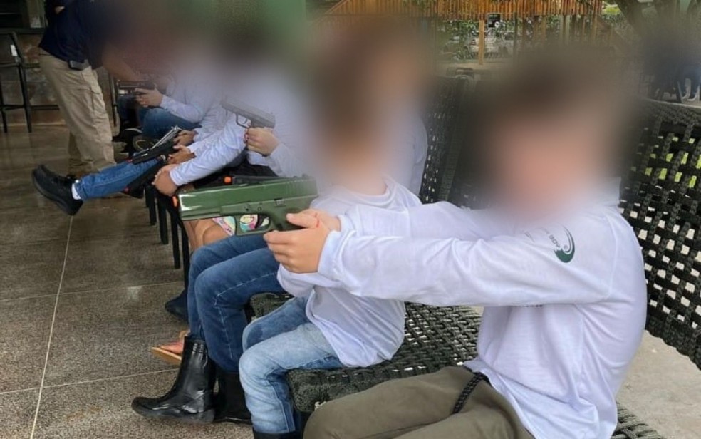 Crianças sentadas enquanto seguram armas em Jataí — Foto: Reprodução/Instagram Hunter Jataí