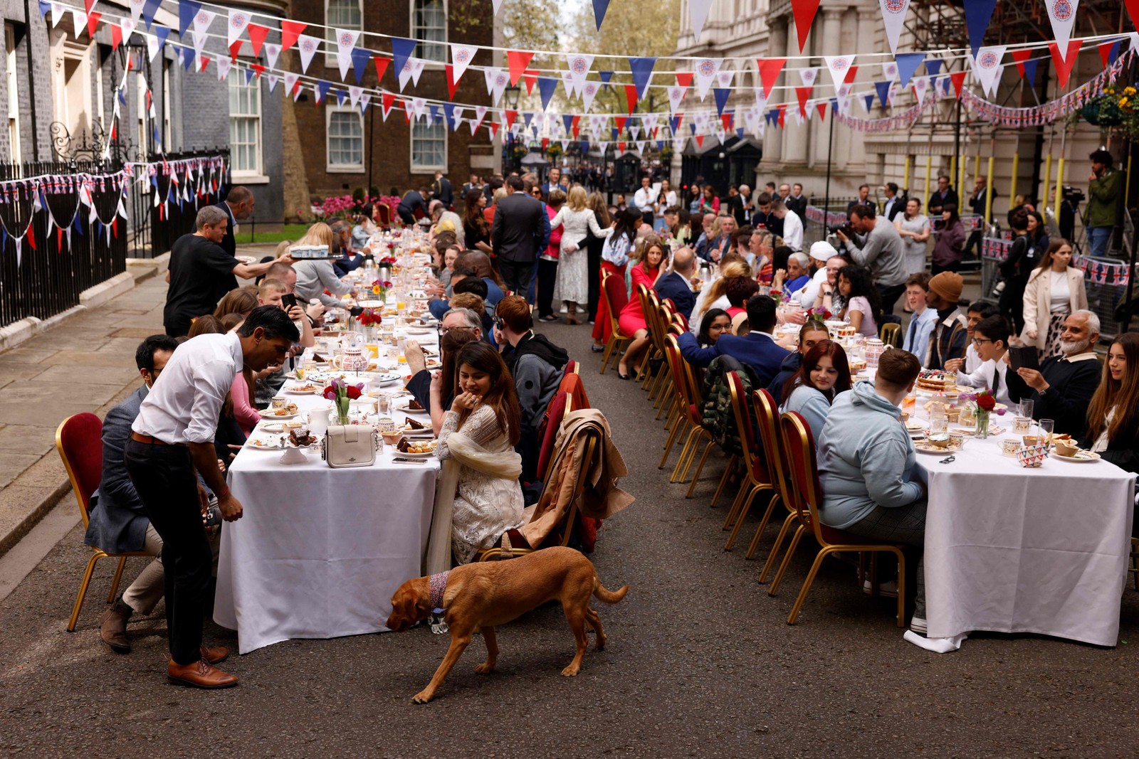 O primeiro-ministro do Reino Unido, Rishi Sunak, olha para seu cachorro durante um grande almoço de coroação organizado em Downing Street, em Londres — Foto: Odd ANDERSEN / AFP