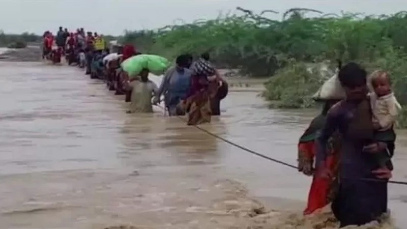 Moradores de vilarejos enfrentam as águas da inundação a caminho das cidades em busca de terrenos mais elevados (Foto: MUHAMMAD AWAIS TARIQ via BBC)