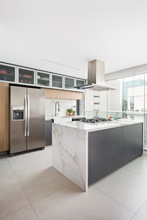 Na cozinha, um móvel baixo tipo bufê camufla a condensadora de ar-condicionado, e o armário alto é usado como despensa. Projeto do escritório Doob Arquitetura 