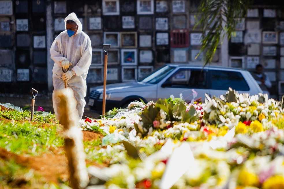 Funcion&aacute;rio com roupa de prote&ccedil;&atilde;o contra o coronav&iacute;rus realiza enterro no Cemit&eacute;rio de Vila Formosa, na Zona Leste de S&atilde;o Paulo. &mdash; Foto: Antonio Molina/Estad&atilde;o Conte&uacute;do