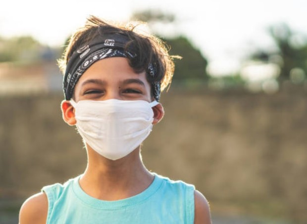Menino de bandana sorrindo com máscara antes de praticar esporte (Foto: Getty Images)